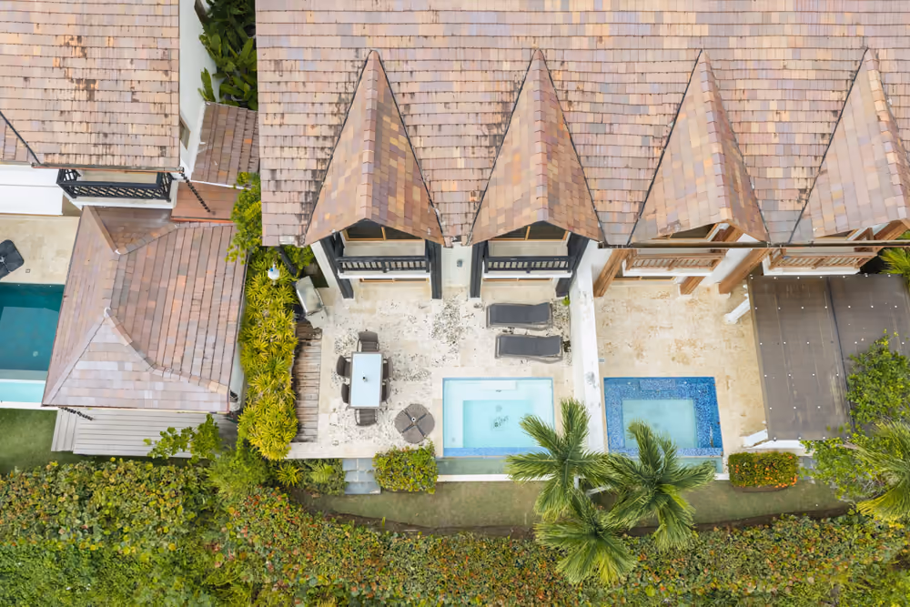 Vista cenital de la terraza con piscina privada, comedor exterior y tumbonas de la villa