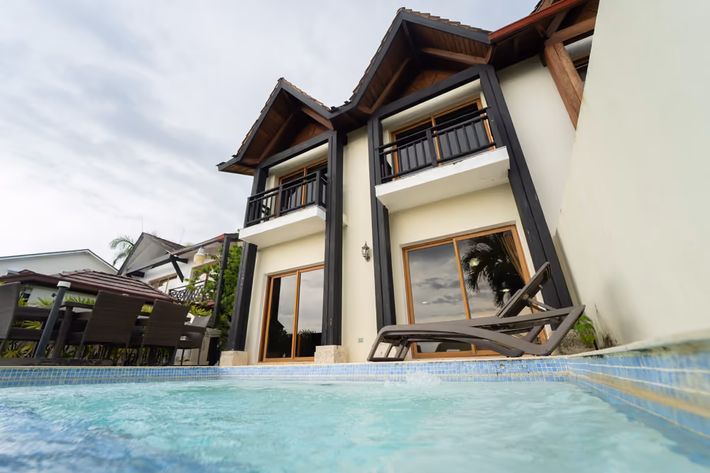 Fachada de dos niveles con balcones, vista desde la piscina privada