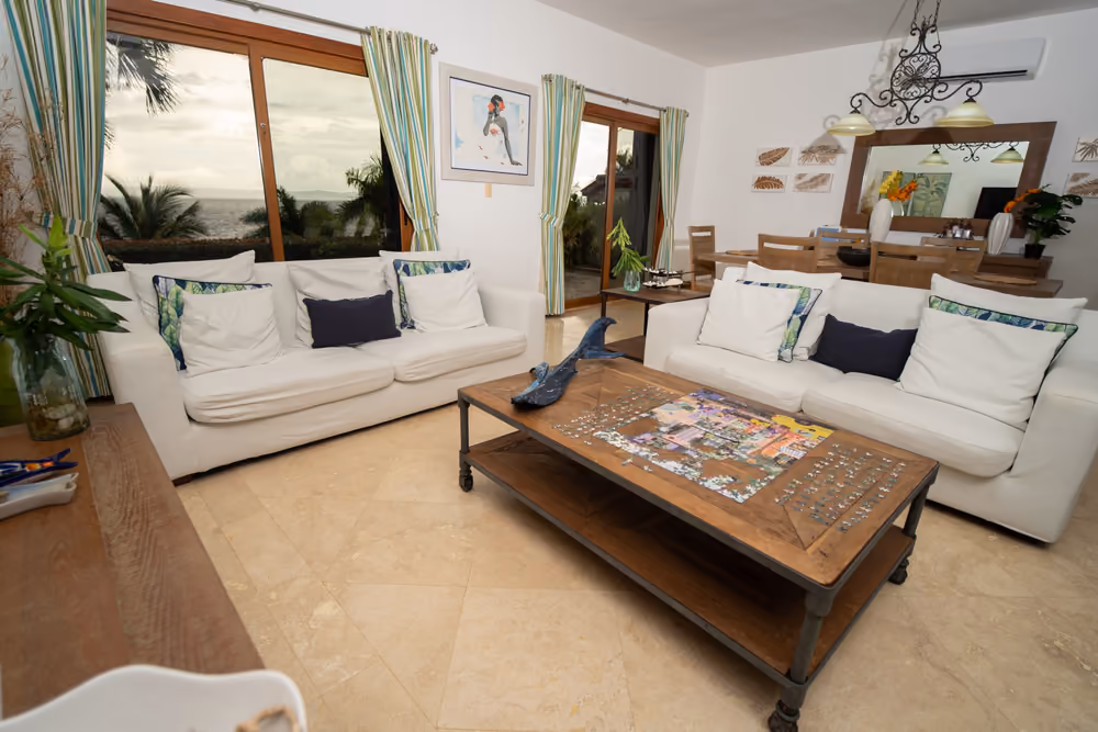 Sala amueblada con sofás blancos y ventanales con vista al mar