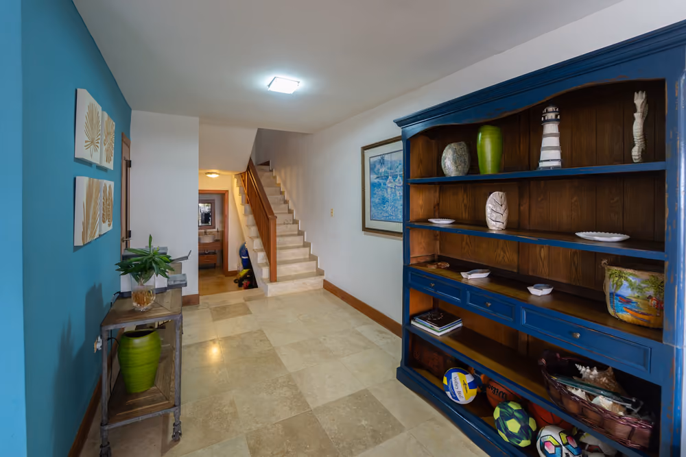Recibidor con escalera al segundo nivel y mueble librero azul