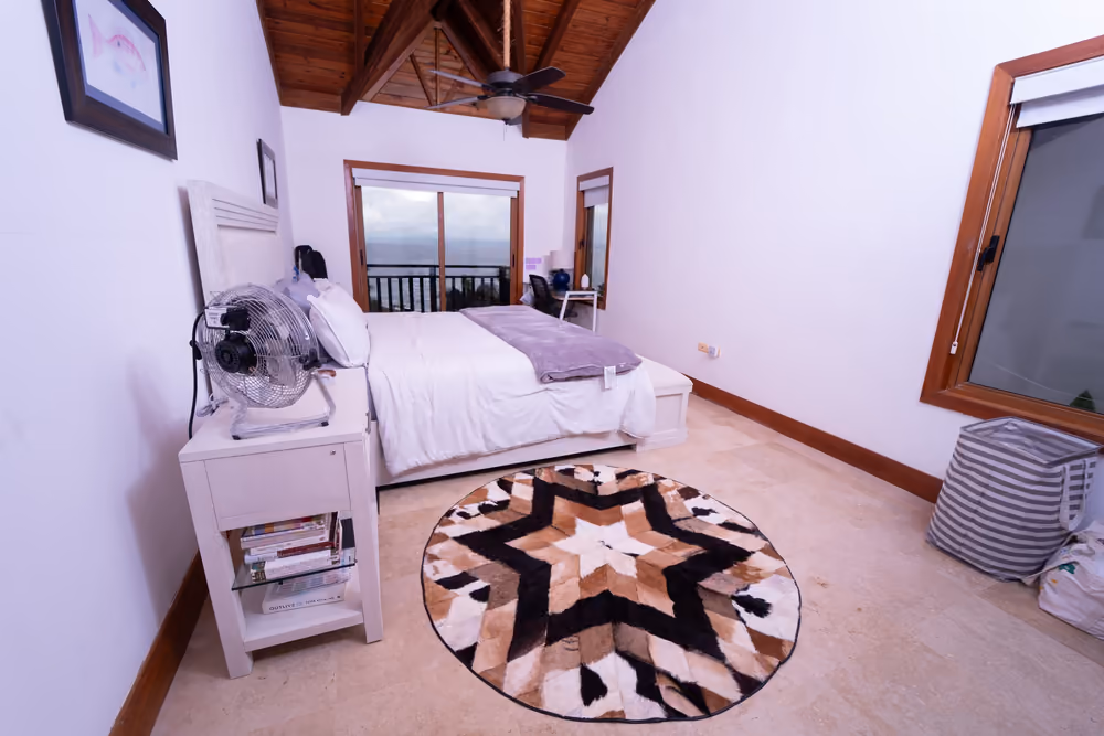 Dormitorio principal con techo de madera a dos aguas y vista al mar