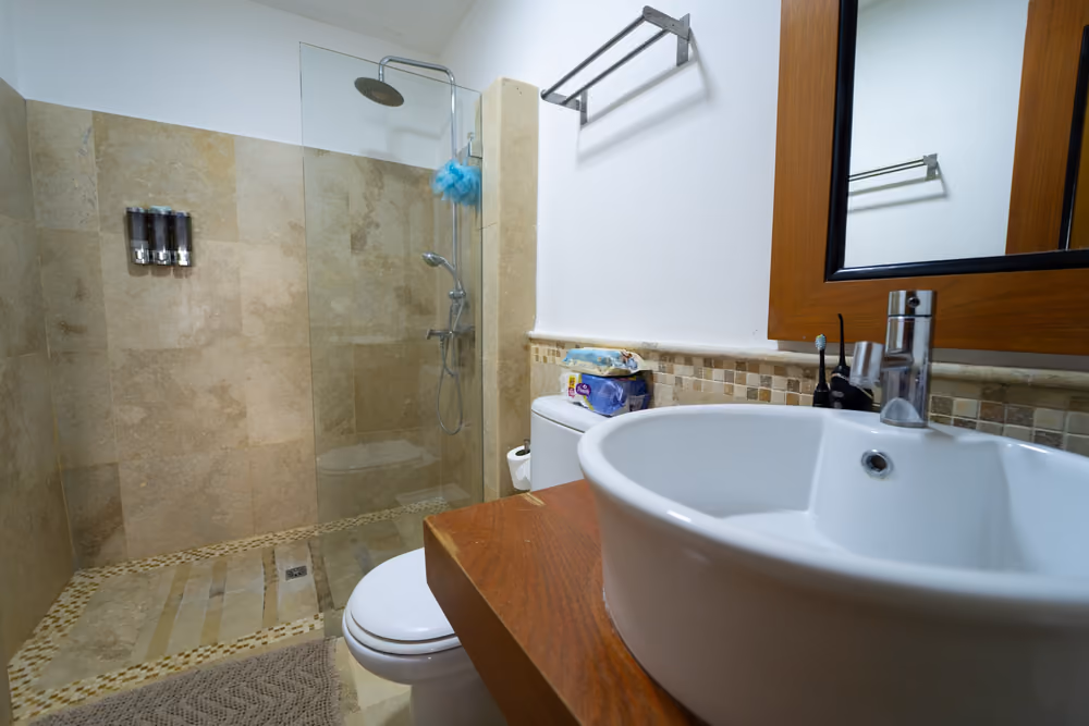 Baño con ducha de lluvia, lavamanos de sobreponer y mueble de madera