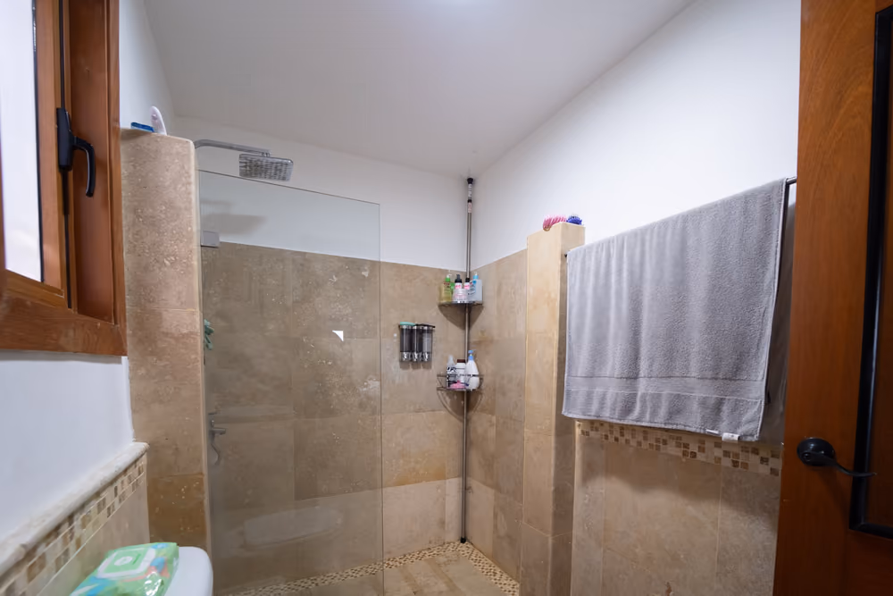 Baño con ducha de cristal y revestimiento de piedra