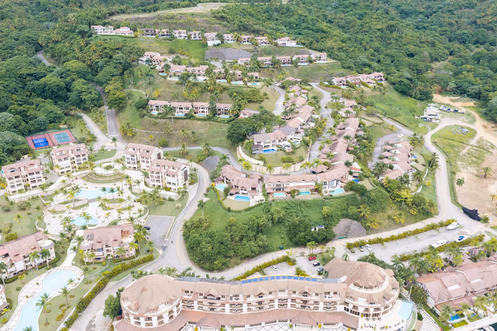 Vista aérea de la comunidad cerrada de Puerto Bahía con villas, piscinas y canchas de tenis