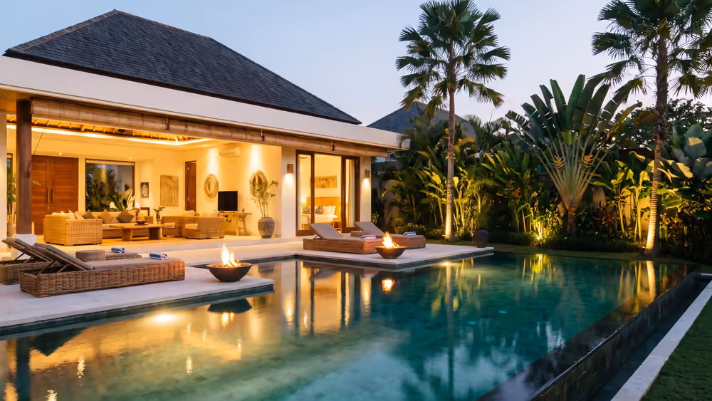Vacation rental villa with a lit pool at dusk